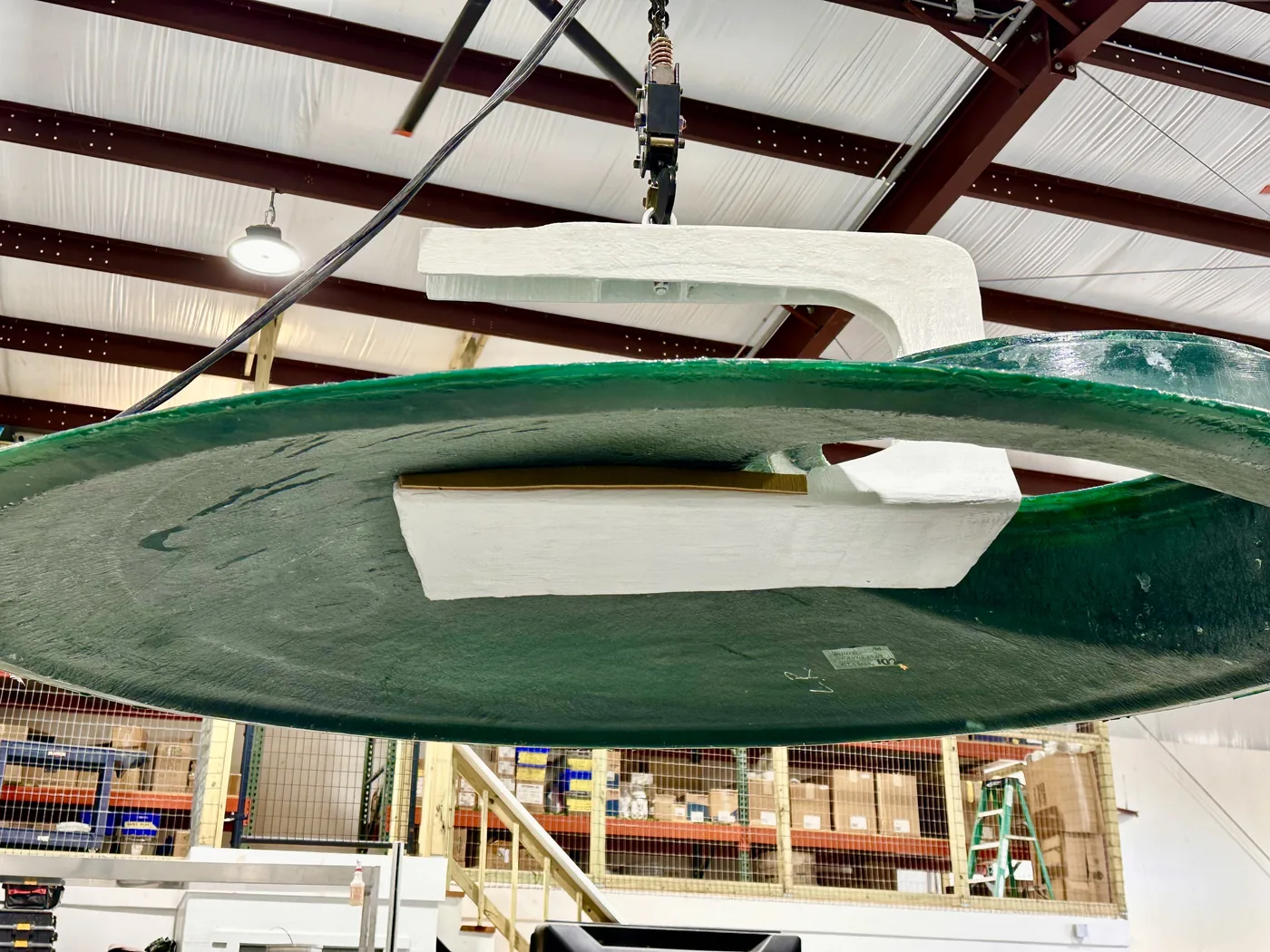 A moulded dome on the shop hoist, lifted clear so the underside and its bonded ribs are visible
